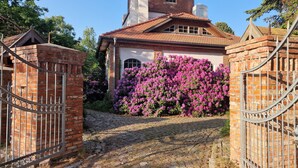 Een bakstenen huis met een dak van rode dakpannen, een pad van stenen en een poort die naar de ingang leidt.
