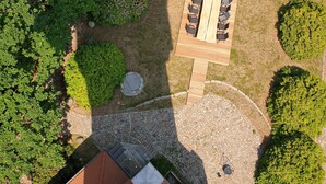 Luchtbeeld van een binnenplaats met een houten terras, zitgedeelte en omliggend groen.