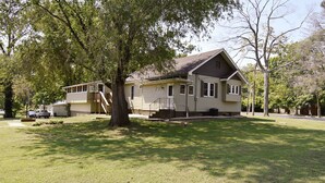A two-story house with a front porch, a covered driveway, and a large tree in front.