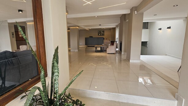A spacious lobby with a sofa, a reception desk, and a TV screen.