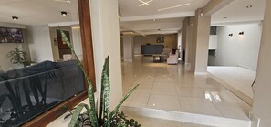 A spacious lobby with a sofa, a reception desk, and a TV screen. - Bariloche Sun Hotel (San Carlos de Bariloche)