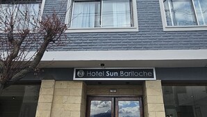 A multi-story hotel with a stone facade, large windows, and a sign reading "Hotel Sun Bariloche."