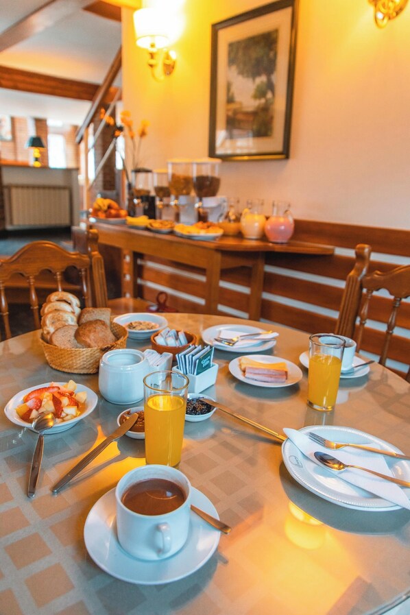 A breakfast table set with various dishes, including bread, fruit, and beverages.