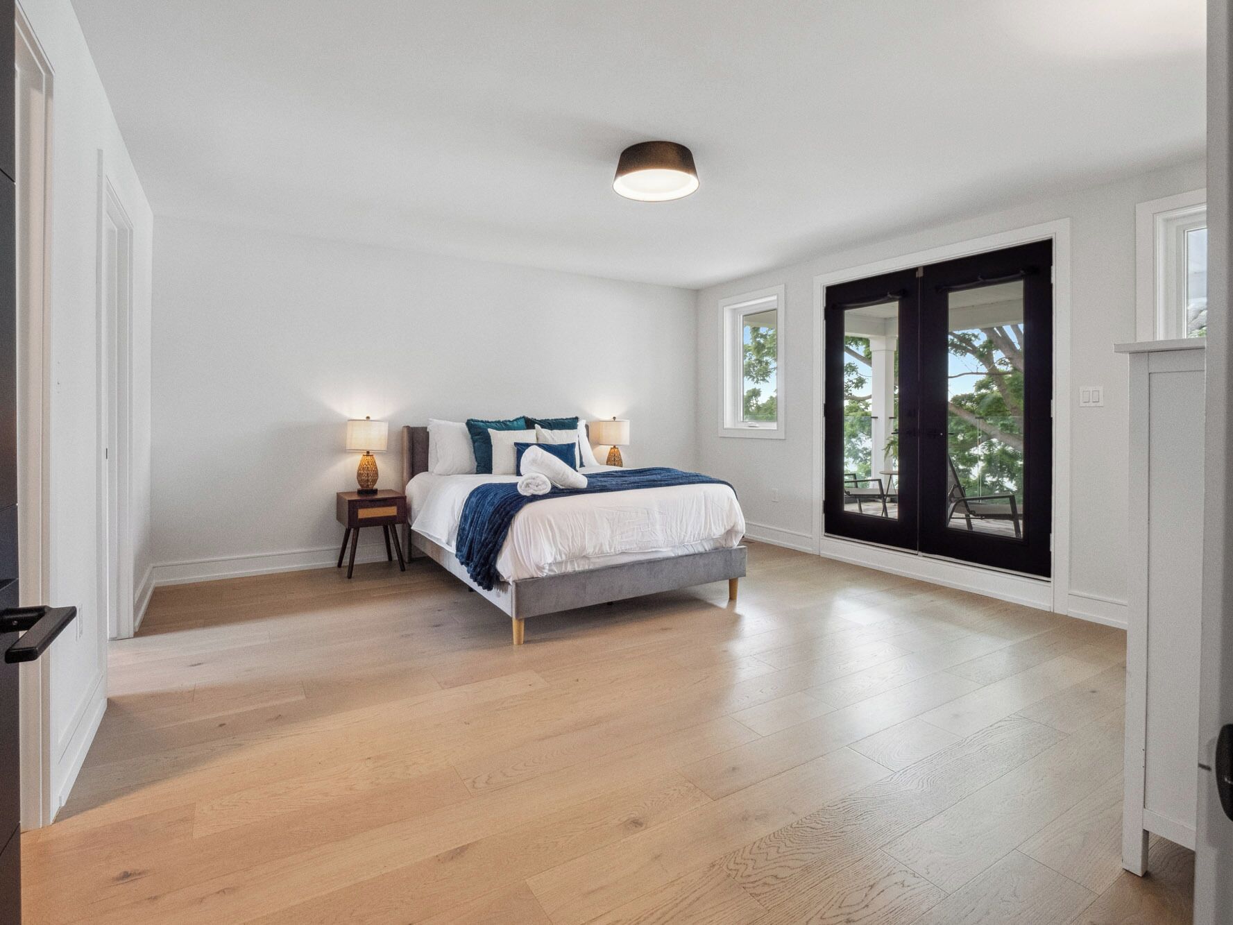 Een slaapkamer met een bed, twee nachtkastjes, een raam en een deur naar een buitenruimte.