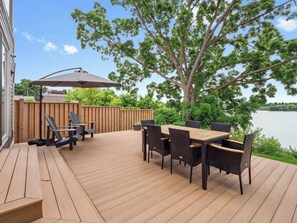 Una terraza de madera con una mesa y sillas, con vista a un lago.