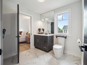 Un baño moderno con inodoro, tocador y un espejo grande.