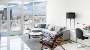 Ein modernes Wohnzimmer mit großem Fenster, einer Couch, einem Couchtisch und einer Stehlampe.