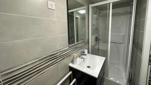 A modern bathroom with a white sink, a mirror, and a glass-enclosed shower.