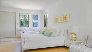 A bedroom with a large bed, a bedside table, a lamp, and framed pictures on the wall.