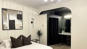 Quarto com cama, mesa de cabeceira, espelho e porta para um banheiro.