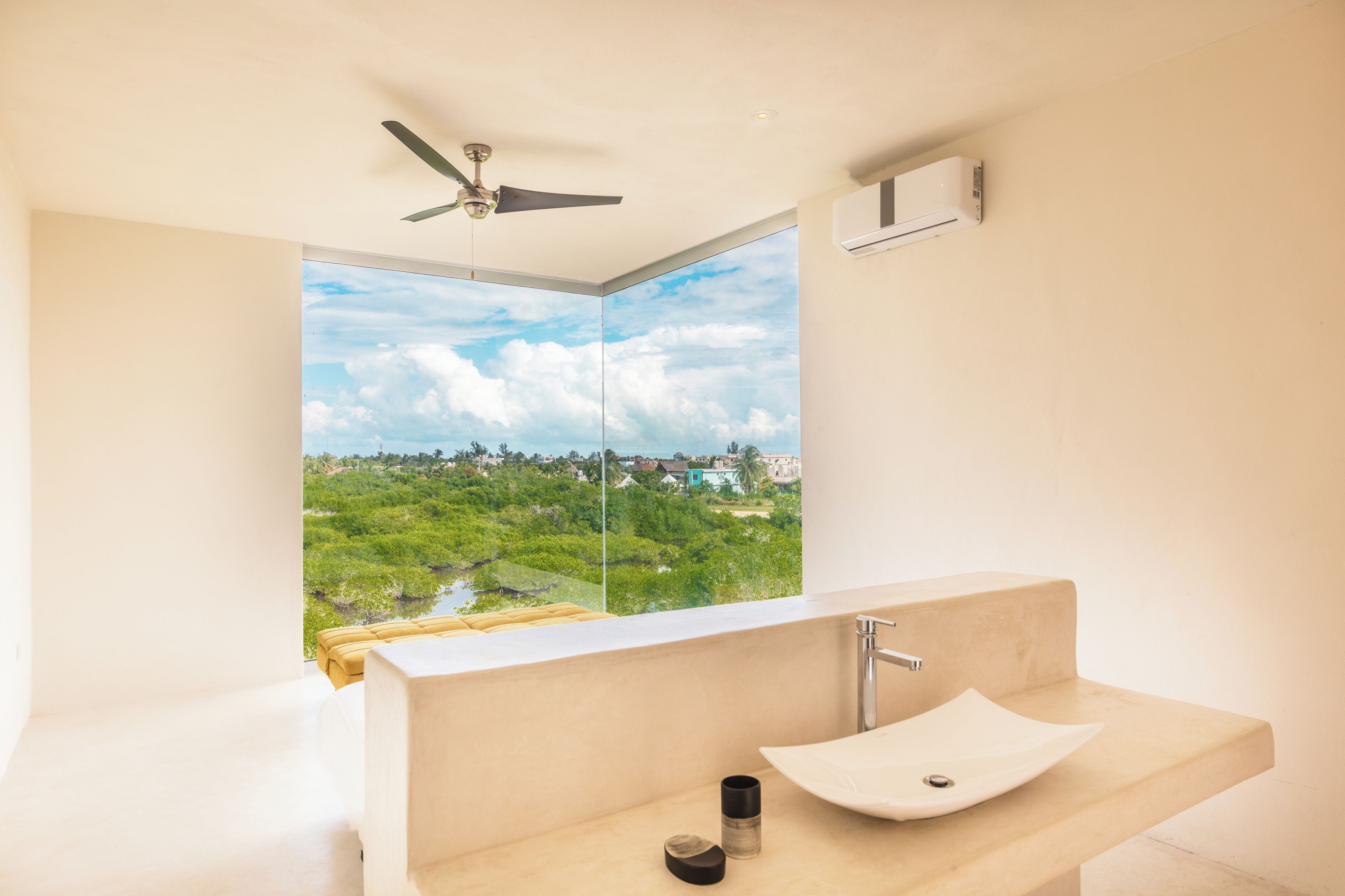 A modern bathroom with a large window, a ceiling fan, and a sink.