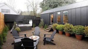Eine moderne Außenpatio mit schwarzen Adirondack-Stühlen, einer Feuerstelle und Topfpflanzen.