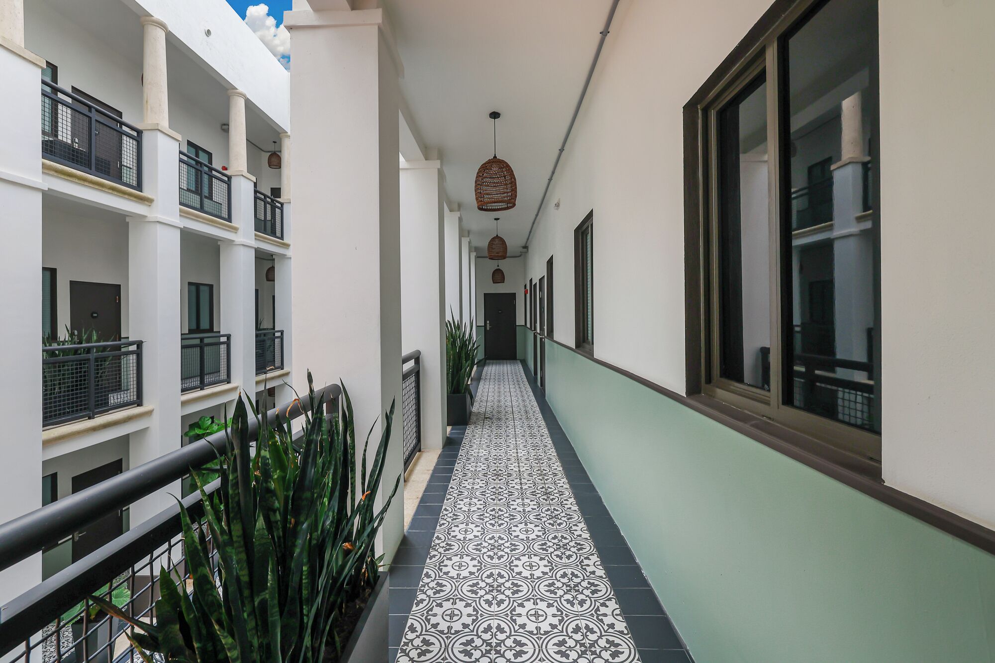 Un pasillo con piso estampado, balcones con barandillas y lámparas colgantes.