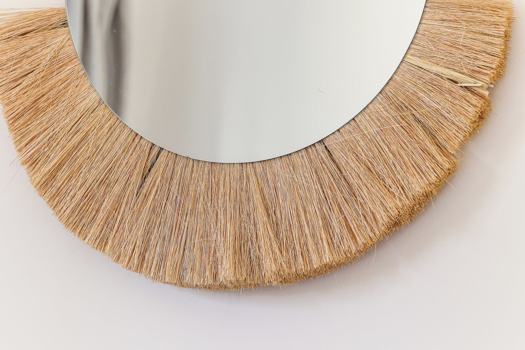 A circular mirror with a textured, straw-like border.