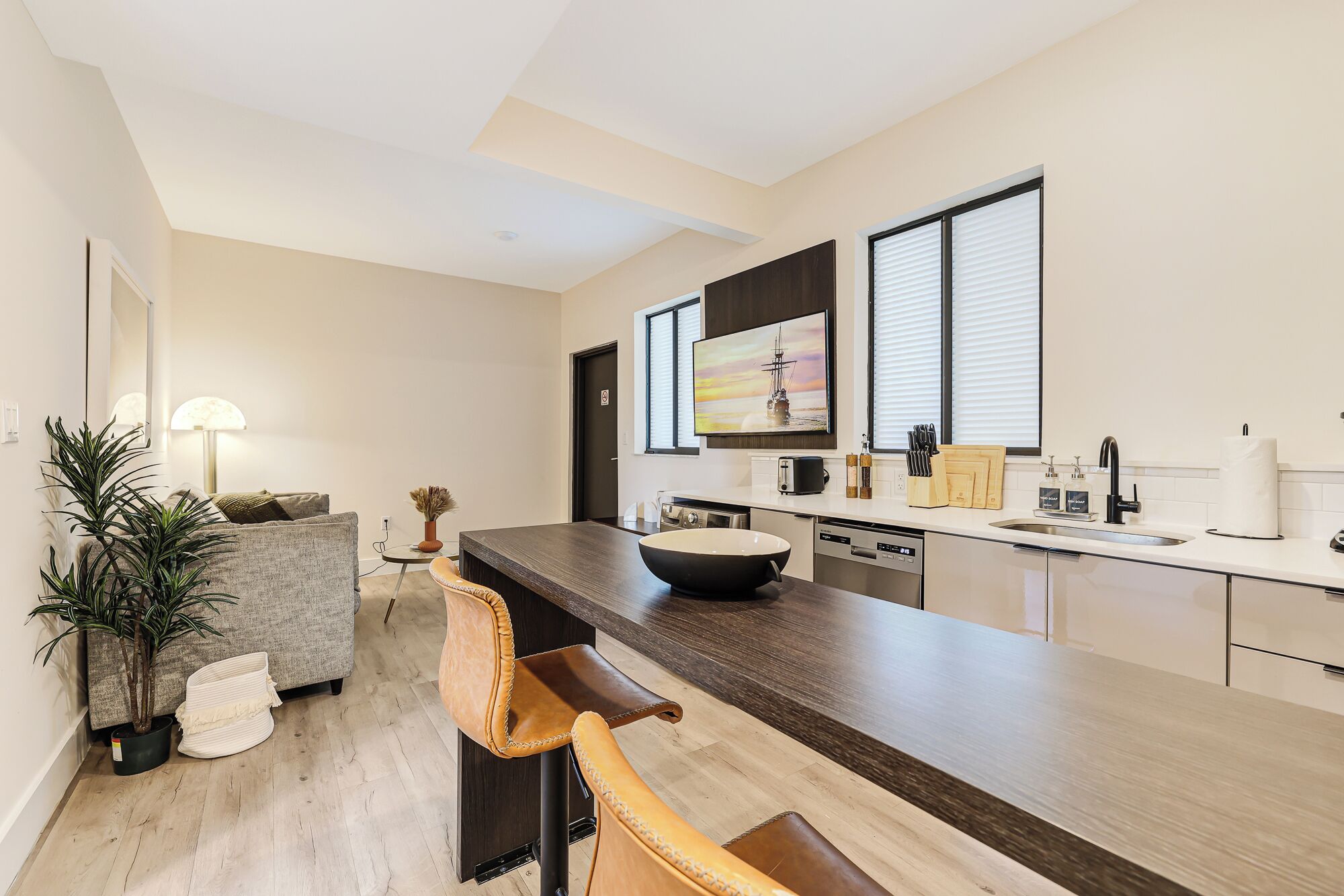 Eine moderne Küche mit einer großen Kochinsel, einem Essbereich mit Stuhl, einer Couch und einem Blumentopf.