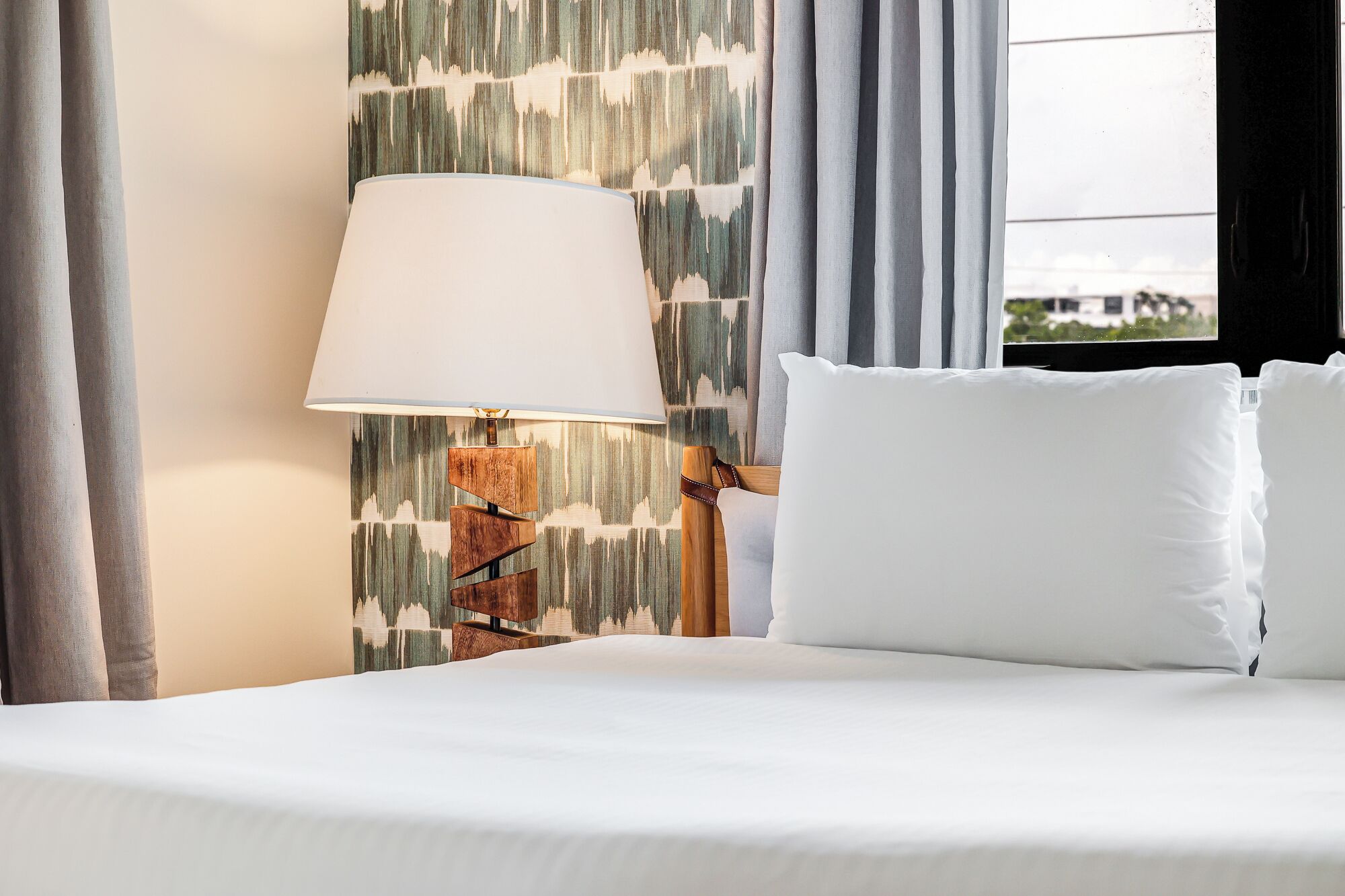 Een hotelkamer met een bed, een lamp en uitzicht op de natuur.