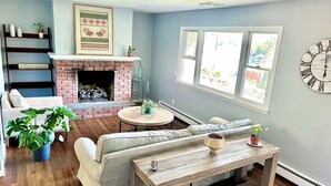 A living room with a brick fireplace, a sofa, a coffee table, and a clock on the wall.