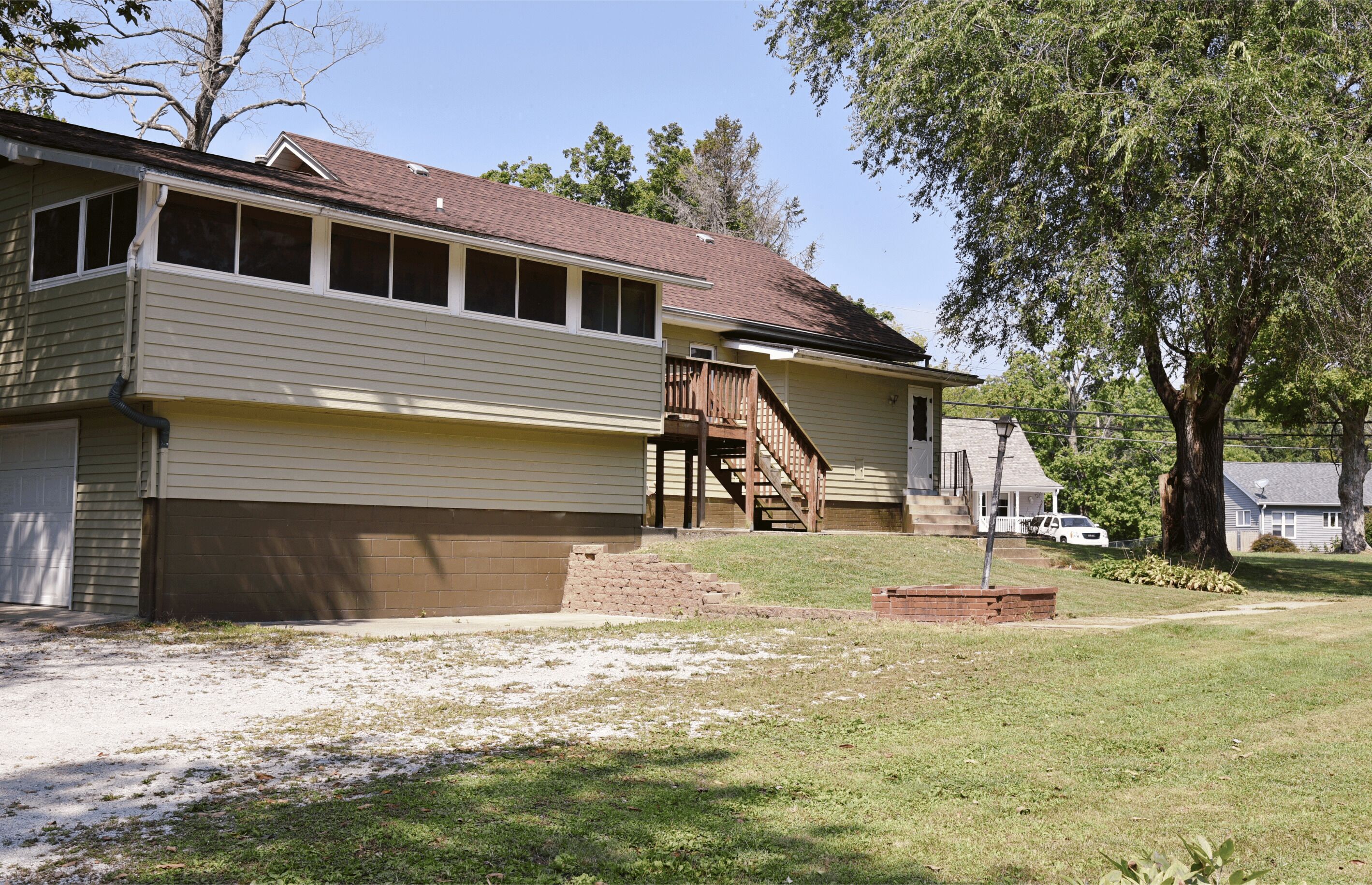 A two-story house with a front porch, a wooden staircase, and a brick foundation.