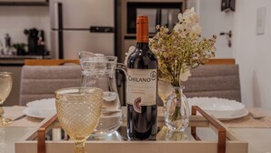 A dining table with a bottle of Chilanó wine, a pitcher, and a vase with flowers. - Arena MRV, 2 quartos,vaga | Brazilian Corner (Belo Horizonte)