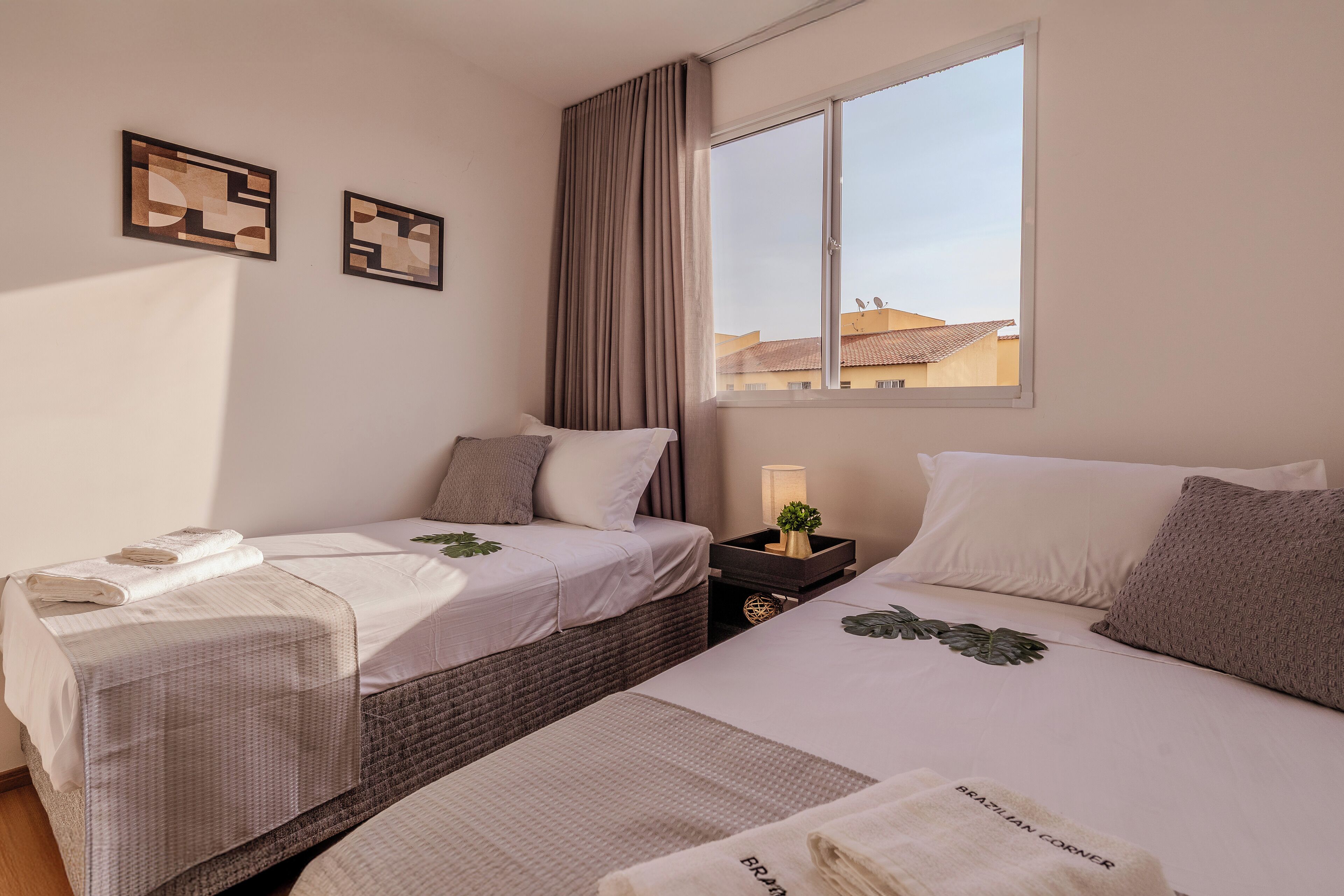 A hotel room with two beds, a large window, and artwork on the wall.
