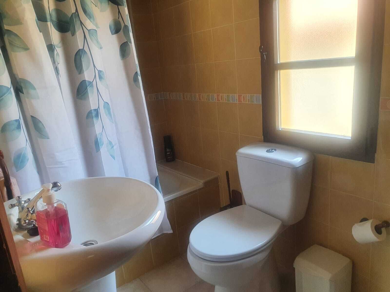 A bathroom with a white sink, toilet, and shower area.