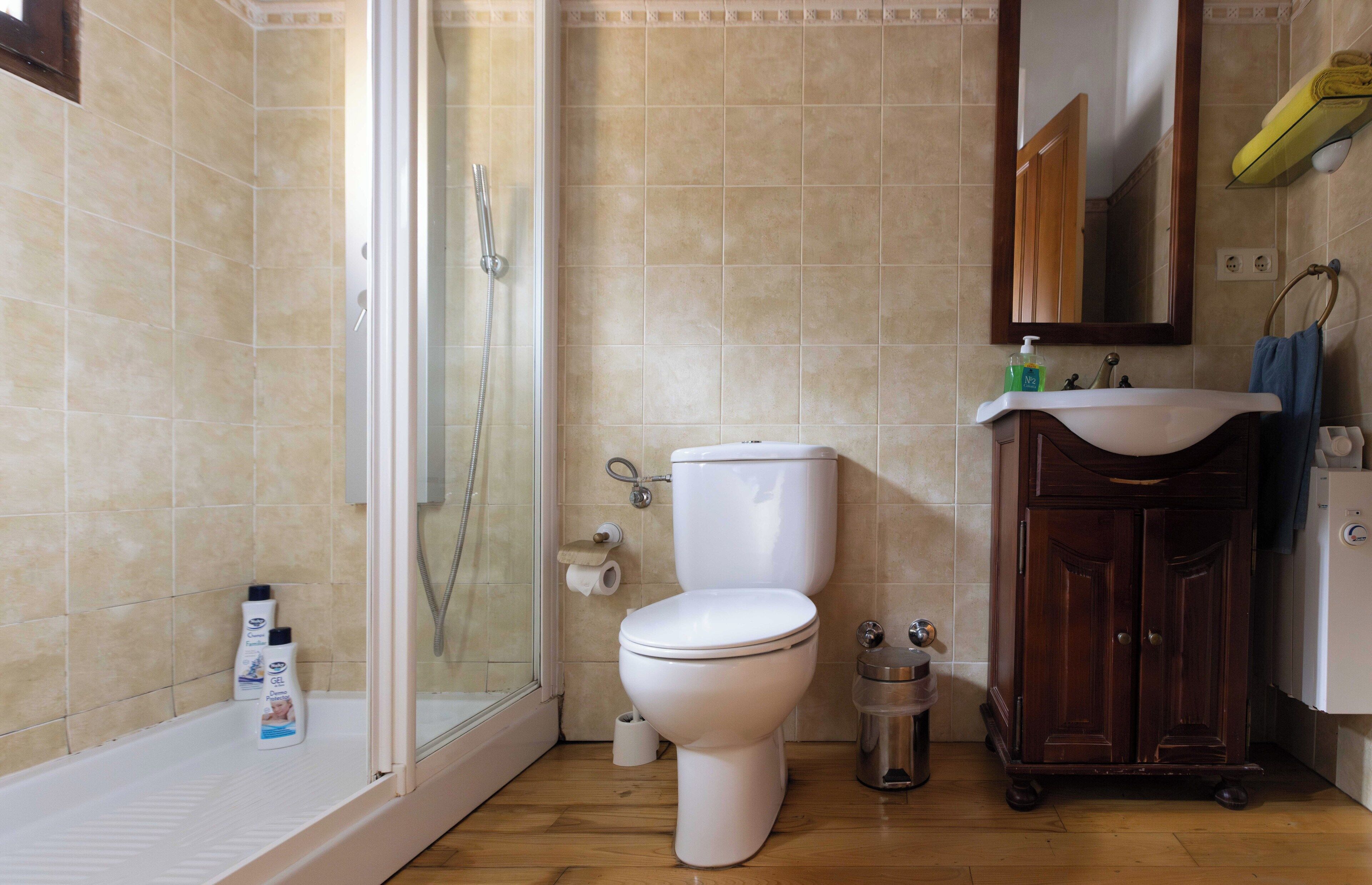 A bathroom with a shower, toilet, sink, and a cabinet.
