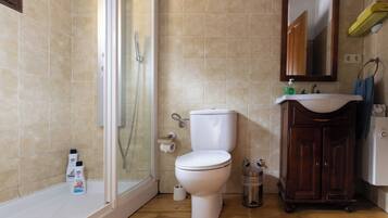 Baño con ducha, inodoro, lavabo y armario.