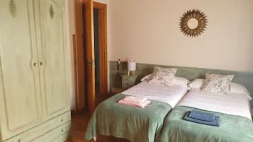A bedroom with two beds, a wardrobe, a mirror, and a nightstand.