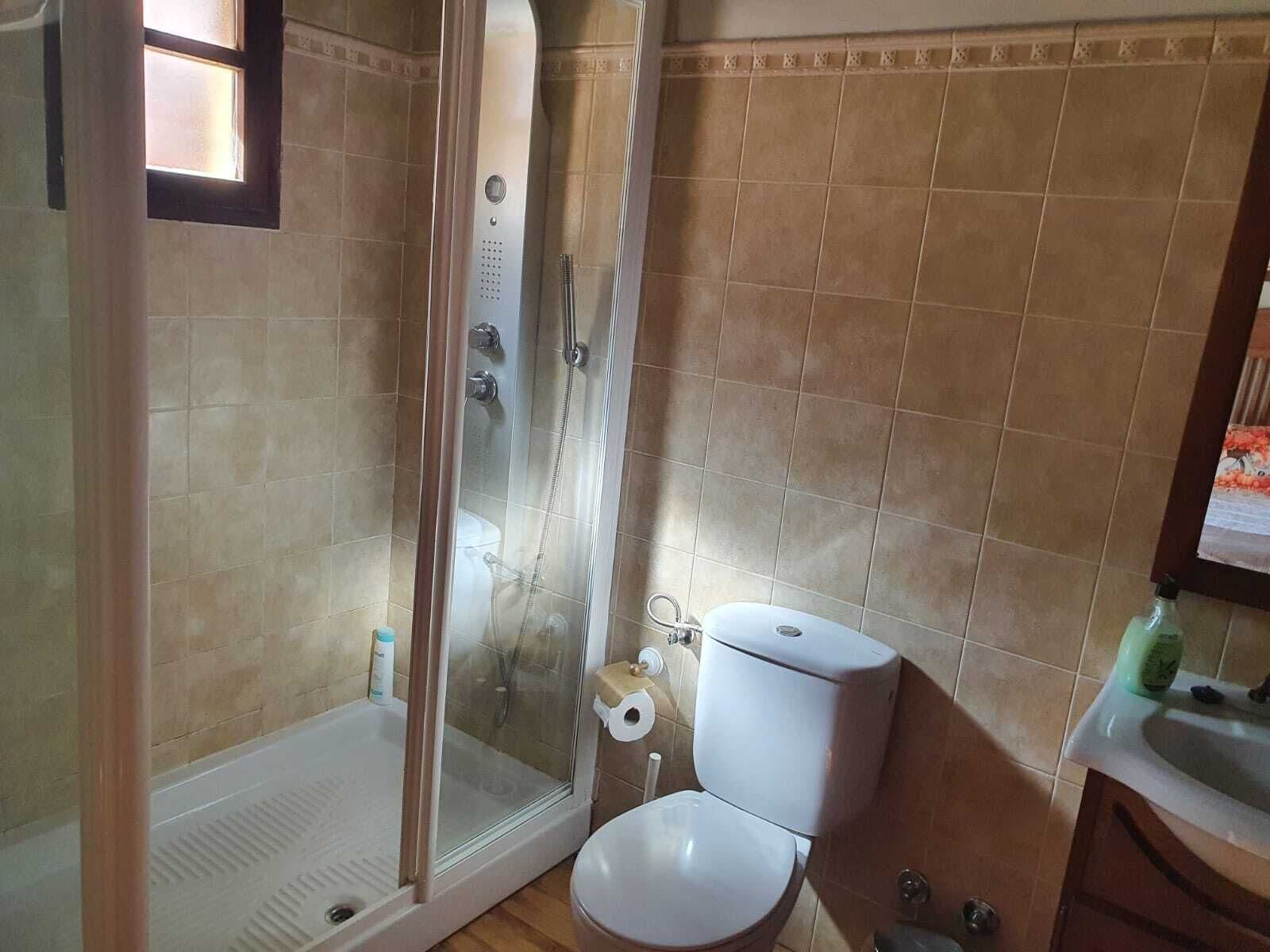 Un baño con ducha acristalada, inodoro y lavamanos.