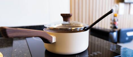 A kitchen with a white pot on an induction cooktop, a wooden handle, and a control panel with various settings.