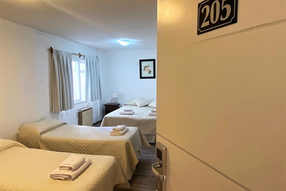 A hotel room with two beds, a small bedside table, a framed picture on the wall, and a number sign indicating room 205.