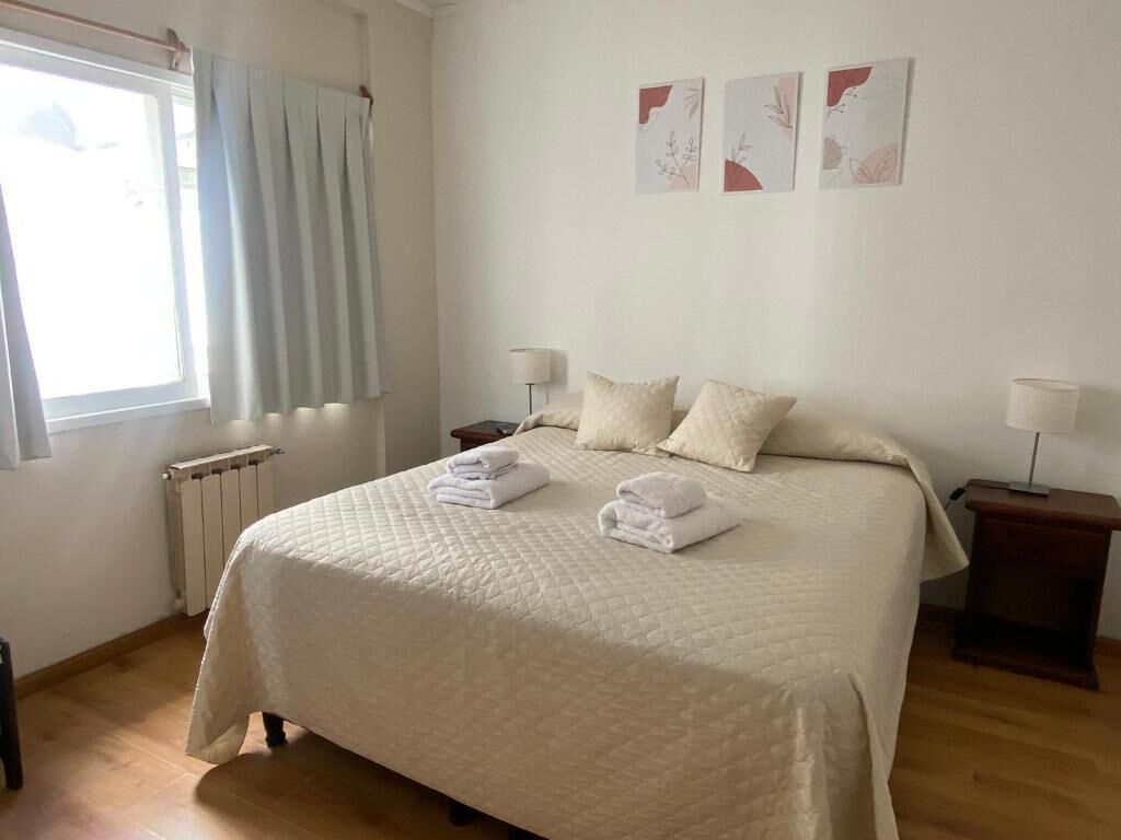 Una camera da letto con un letto grande, due comodini, un termosifone e una finestra con tende.