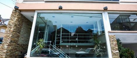 L’hôtel Garden Bariloche se distingue par sa façade moderne, ses éléments décoratifs en pierre et son entrée en verre transparent.