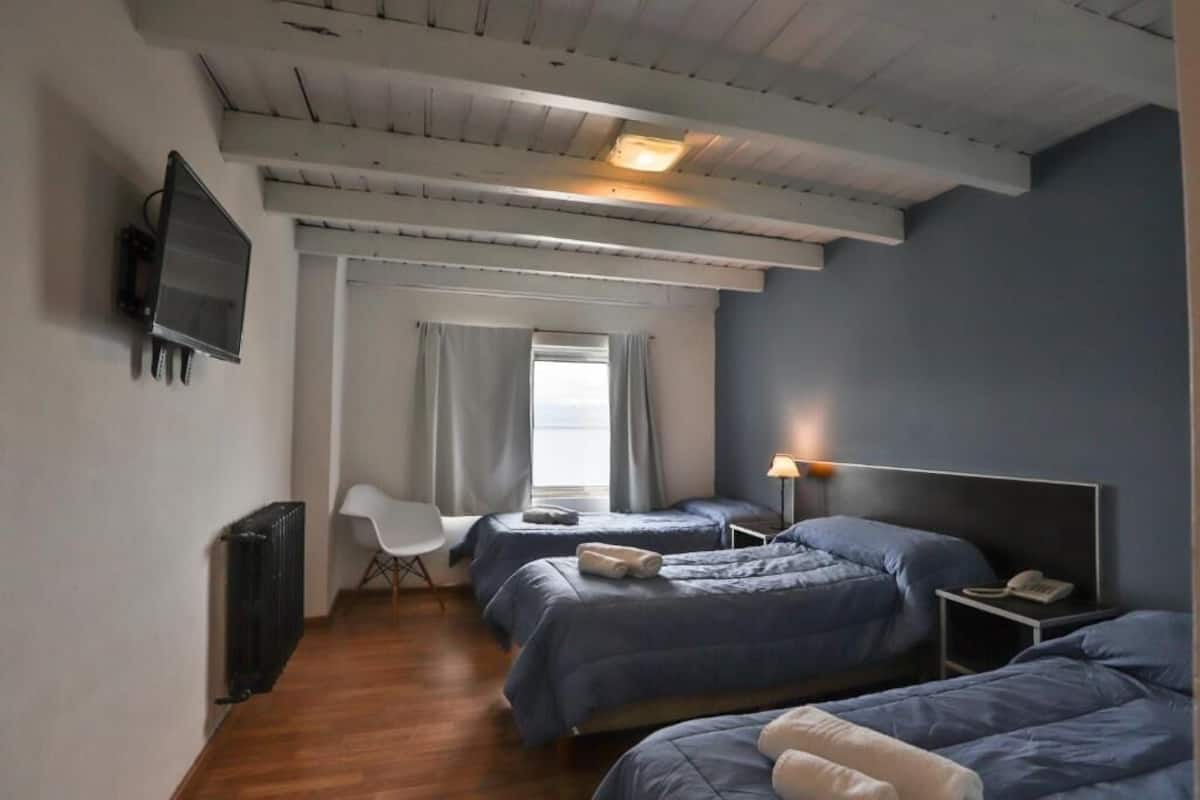 A hotel room with two beds, a TV, a desk, and a chair.