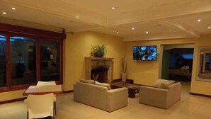 Una sala de estar amplia con chimenea, asientos cómodos, televisor y un ventanal grande.