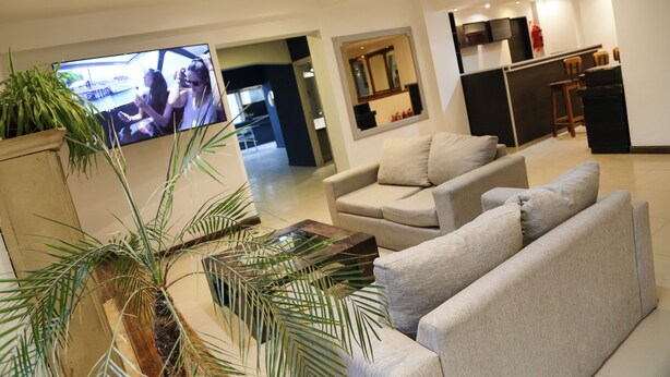Una sala de estar moderna con un televisor de pantalla plana, un sofá, una mesita de centro y una planta en maceta.