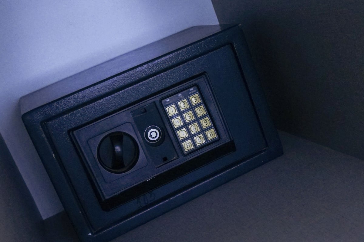 A black safe with a keypad and a keyhole, placed in a corner.
