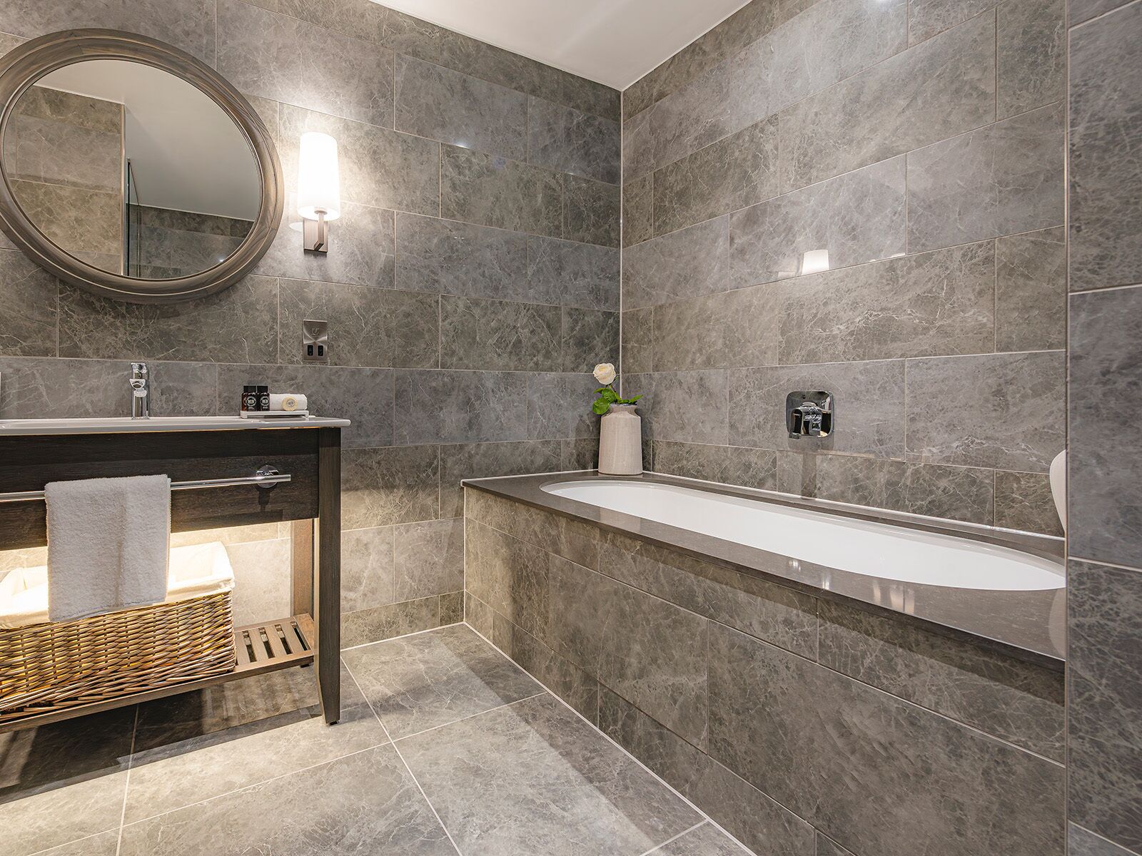 Un baño moderno con un espejo grande, una bañera y un tocador con toallero.