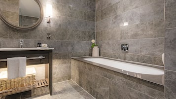 Un baño moderno con un espejo grande, una bañera y un tocador con toallero.