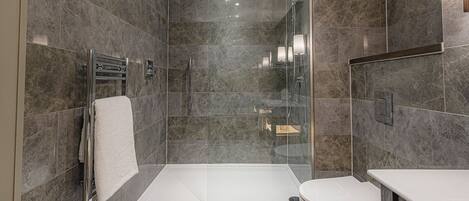 A modern bathroom with a glass-enclosed shower, a white toilet, and a vanity with a mirror.