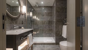 Un baño moderno con ducha de vidrio, una bañera independiente y un tocador con espejo.