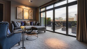A modern living room with a sofa, armchairs, and a coffee table. Large windows offer a view of the cityscape. - Dakota Newcastle (Newcastle-upon-Tyne)