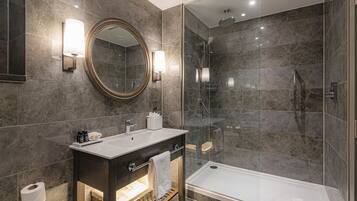 A modern bathroom with a large mirror, a vanity with a sink, a shower enclosure, and a bathtub.