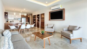 Una sala de estar moderna con un sofá, dos sillones, una mesa de centro y un comedor con sillas y una mesa.