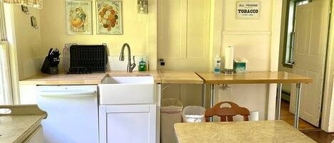 Une cuisine compacte comprenant un évier, un petit réfrigérateur et un coin repas avec une table et des chaises.