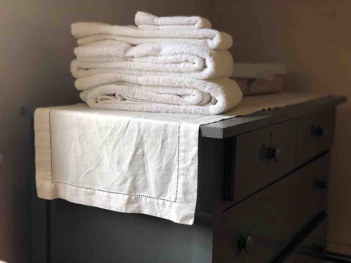 A stack of white towels on a table with a white cloth cover.