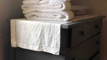 A stack of white towels on a table with a white cloth cover.