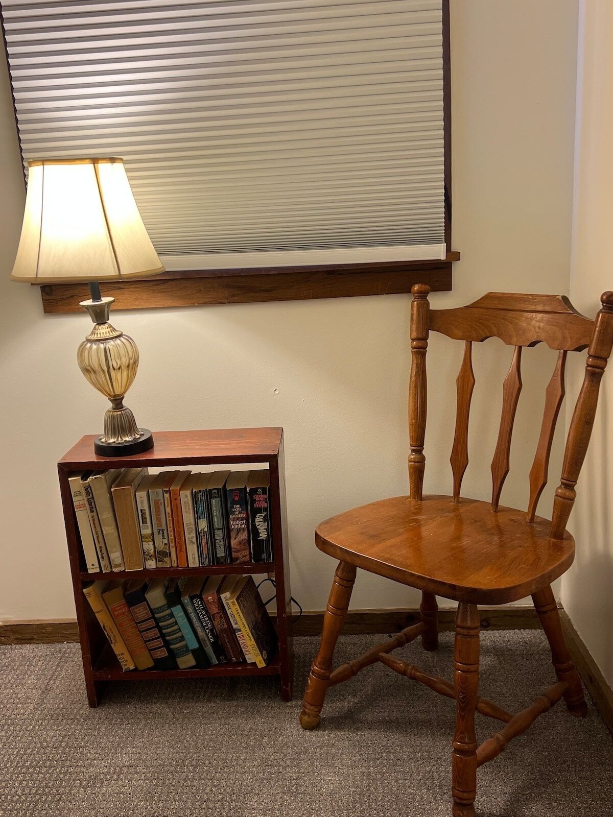 A wooden chair and a bookshelf with books.