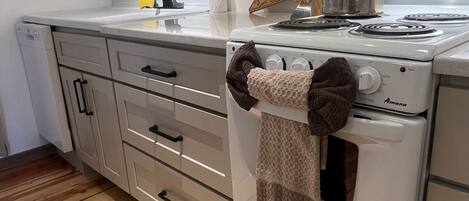 A kitchen with a white stove, wooden flooring, and a knife block on the counter.