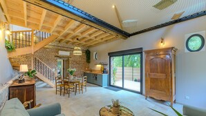 Amplia sala de estar con una escalera de madera, una mesa de comedor y un gran aparador de madera.